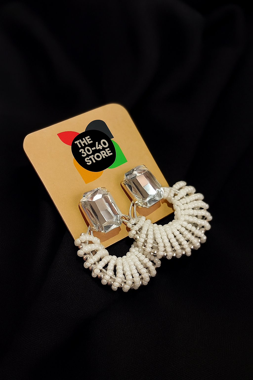 Elegant beaded hoop earrings with gemstone studs on a brown card displaying The 30-40 Store logo, placed on a black fabric background.