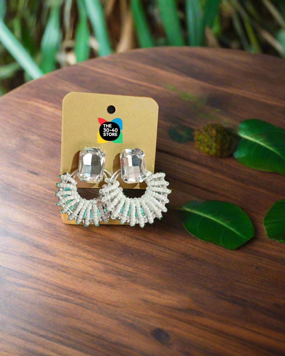 Pair of silver hoop earrings on a branded card against a black fabric background