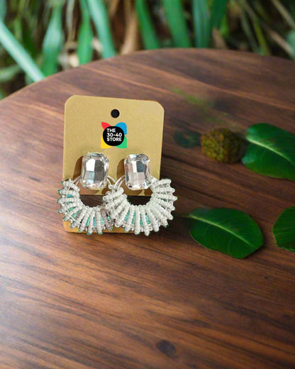 Pair of silver hoop earrings on a branded card against a black fabric background