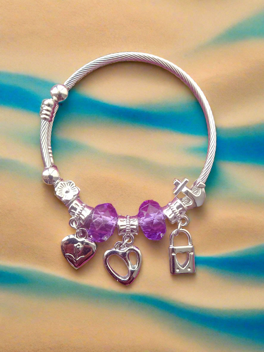 Silver bracelet with charms on a pink textured background